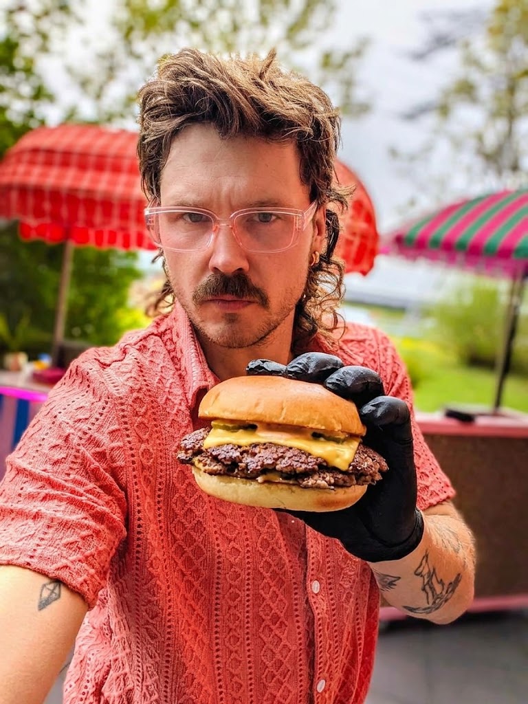 Arthur houdt een verse smashburger omhoog bij de kar